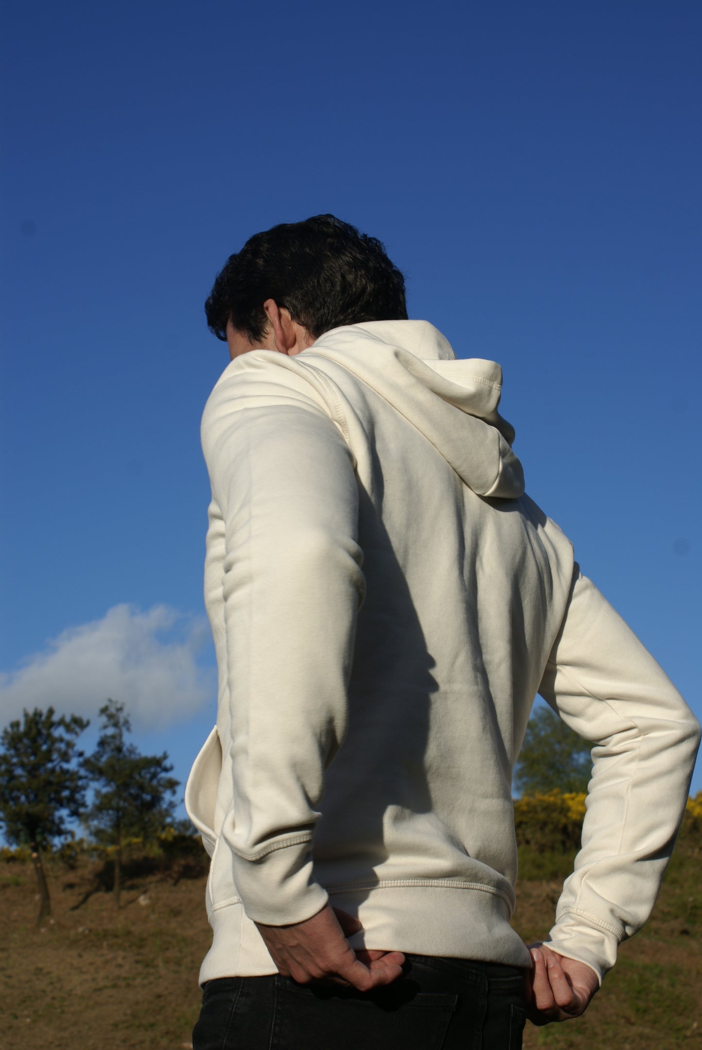A man walks by, he's wearing an Off White Organic Cotton Hoodie from the Be Kind Apparel Original Collection
