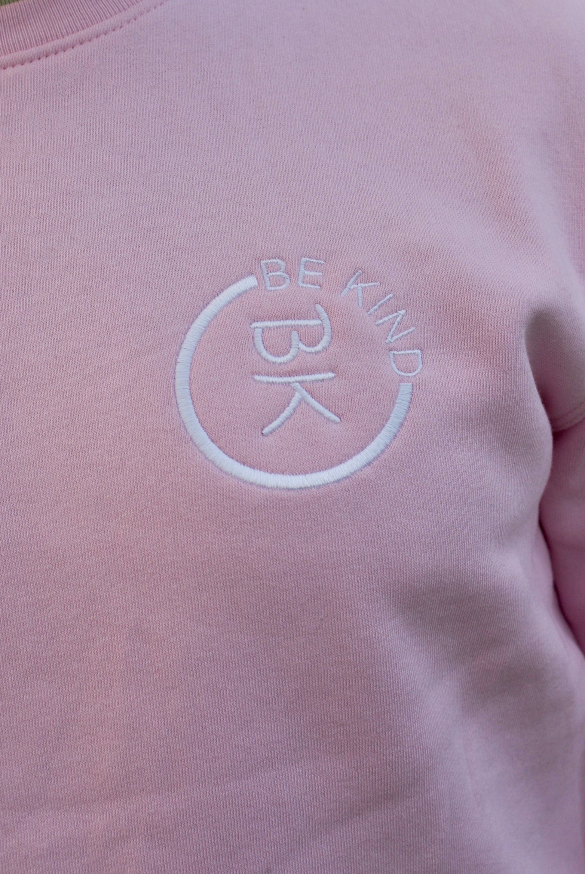 A man stands looking forward, he's wearing a Bubblegum Pink Organic Cotton Sweatshirt from the Be Kind Apparel Original Collection