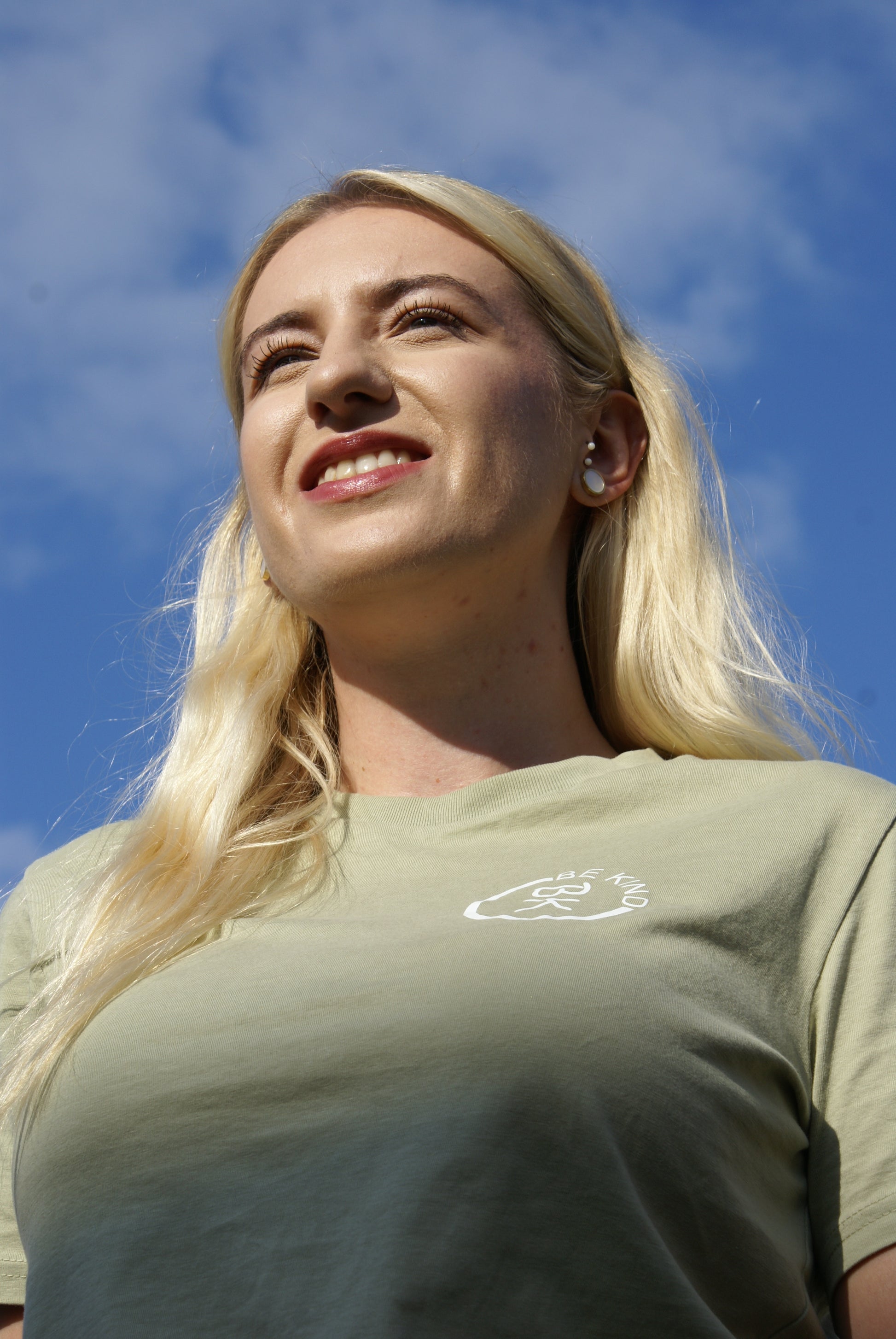 A woman looks into the distance, she's wearing an Olive Green Organic Cotton T-Shirt from the Be Kind Apparel Original Collection