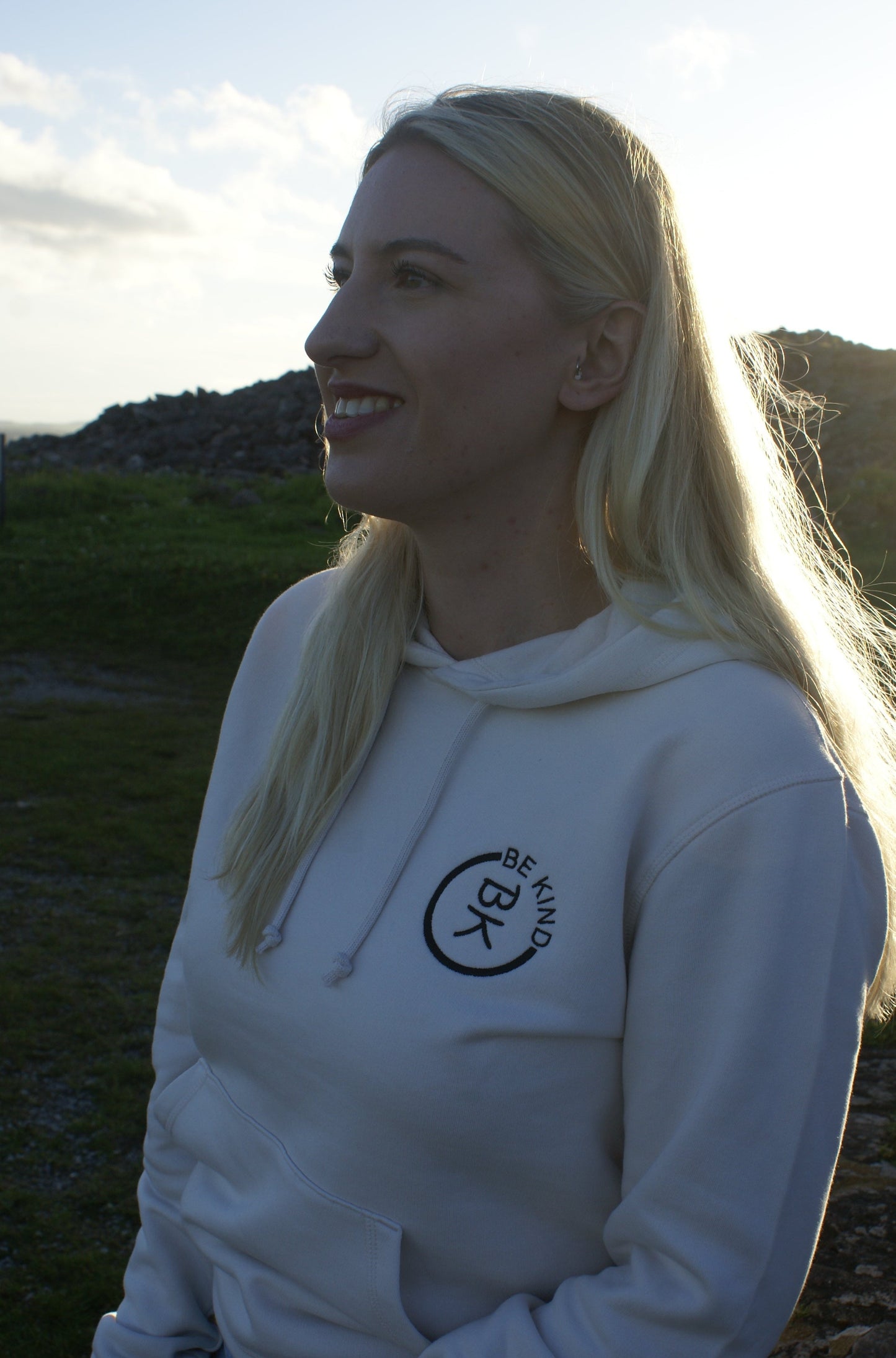 A woman looks out, she's wearing an Off White Organic Cotton Hoodie from the Be Kind Apparel Original Collection