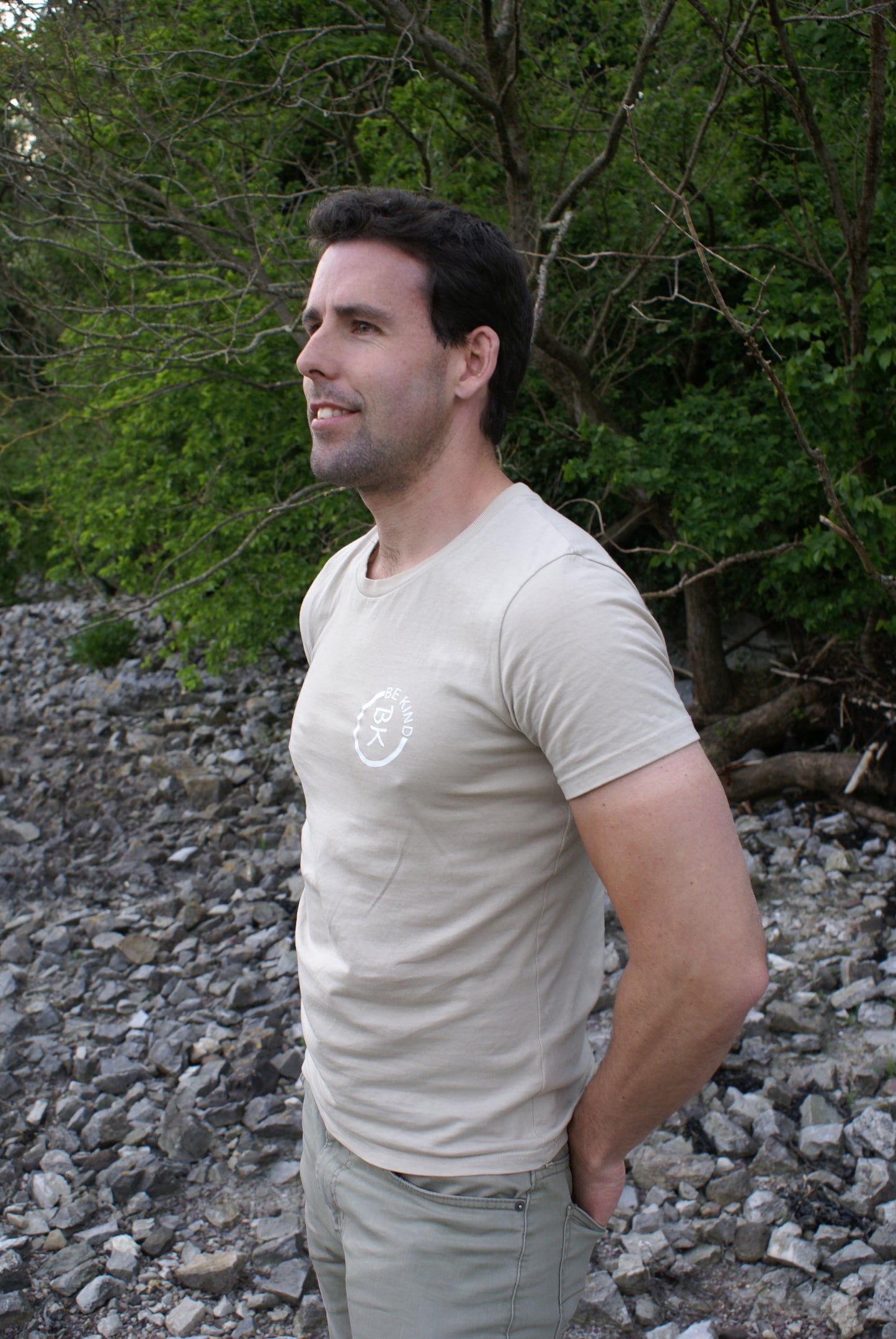 A man looks out, he's wearing a Sandstone Beige Organic Cotton T-Shirt from the Be Kind Apparel Original Collection
