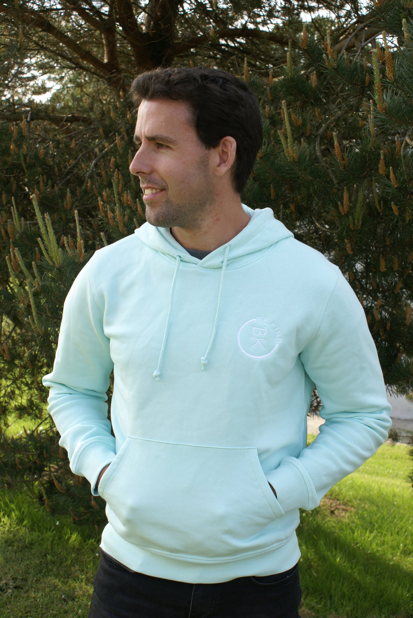 A man looks away, he's wearing a Mint Green Organic Cotton Hoodie from the Be Kind Apparel Original Collection