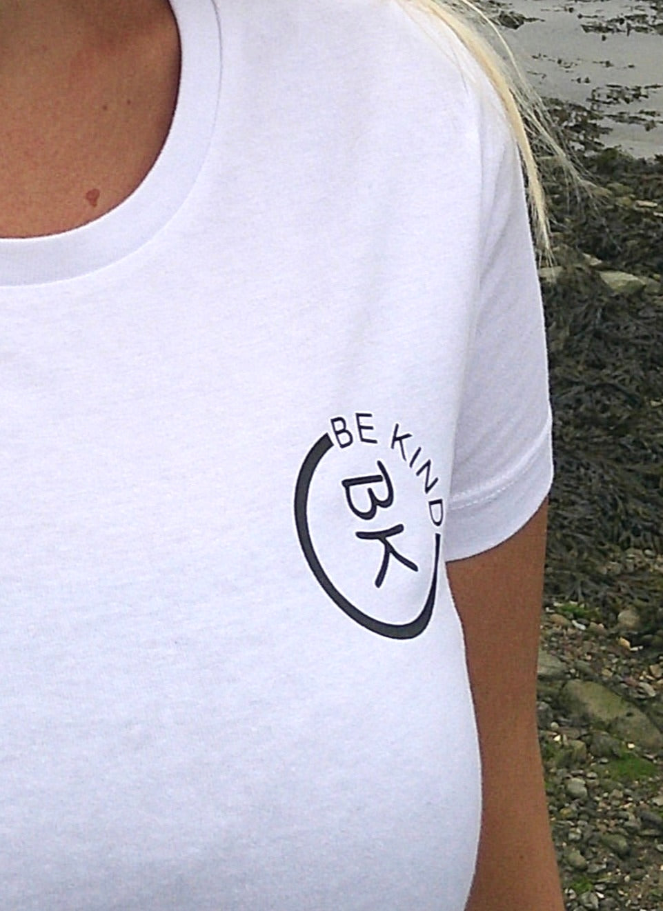 A woman stands, she's wearing a White Organic Cotton Connector T-Shirt from the Be Kind Apparel Connector Range