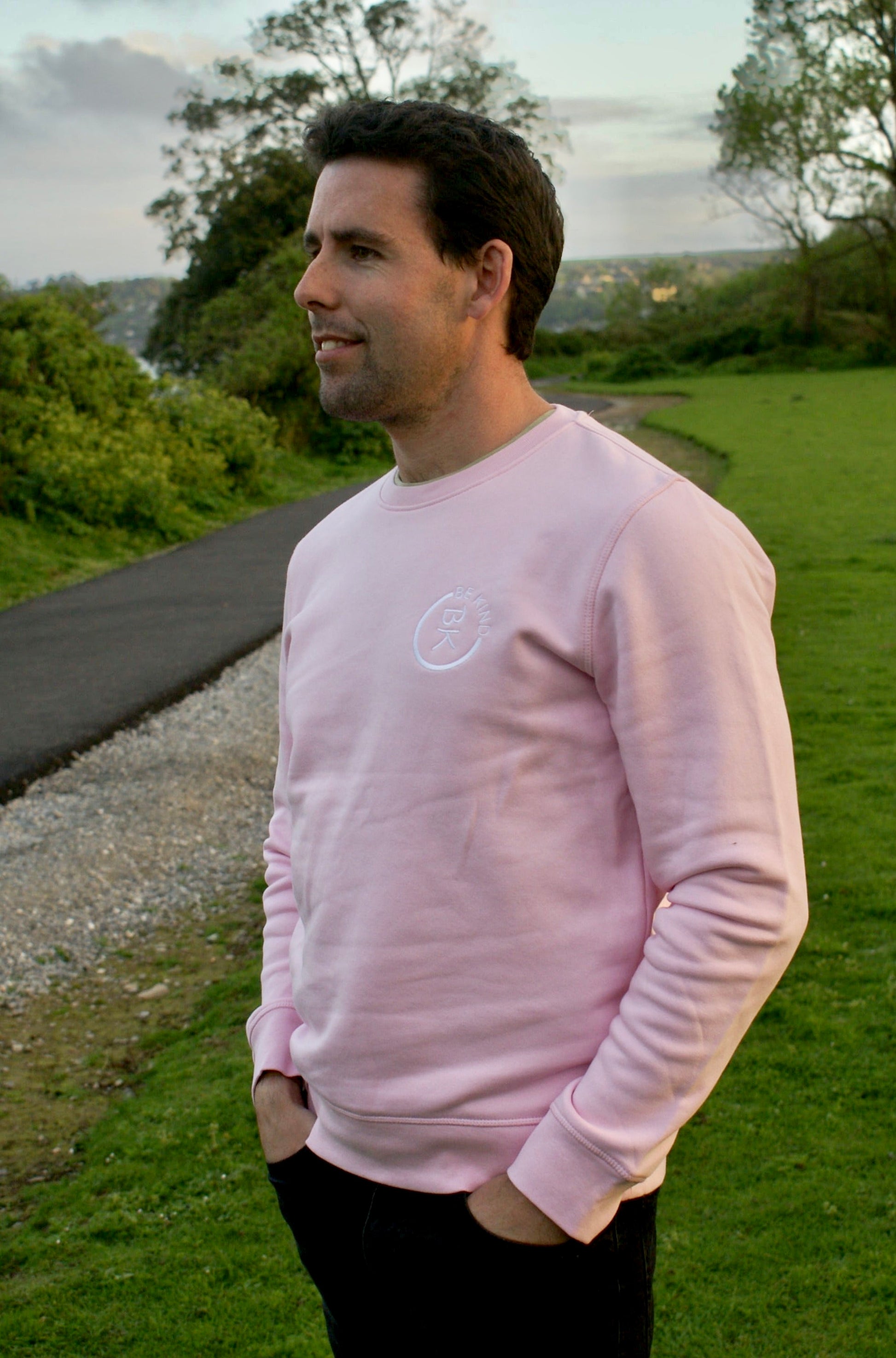 A man looks out, he's wearing a Bubblegum Pink Organic Cotton Sweatshirt from the Be Kind Apparel Original Collection